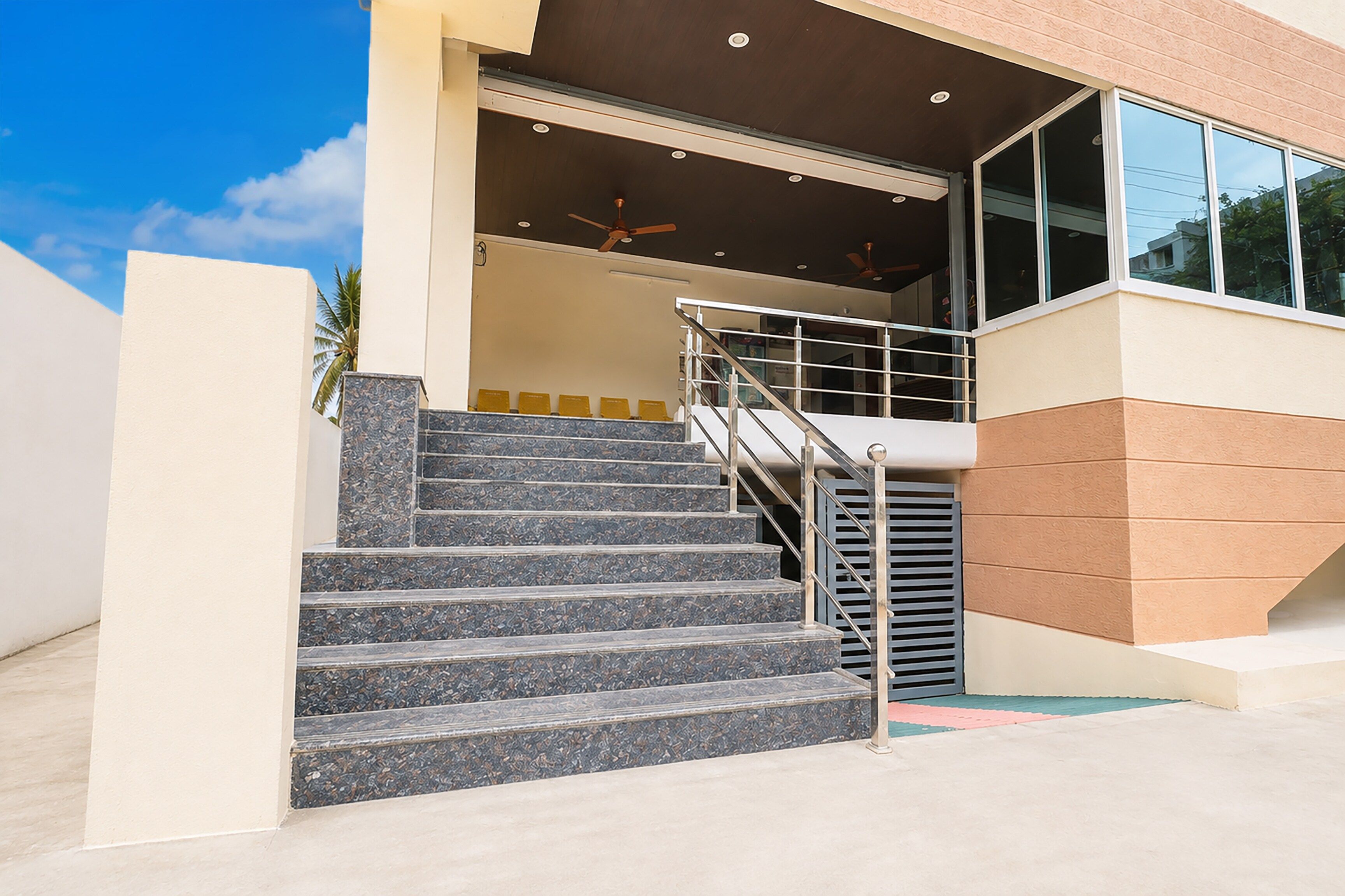 A staircase leading to a building entrance with a handrail and a ceiling fan.