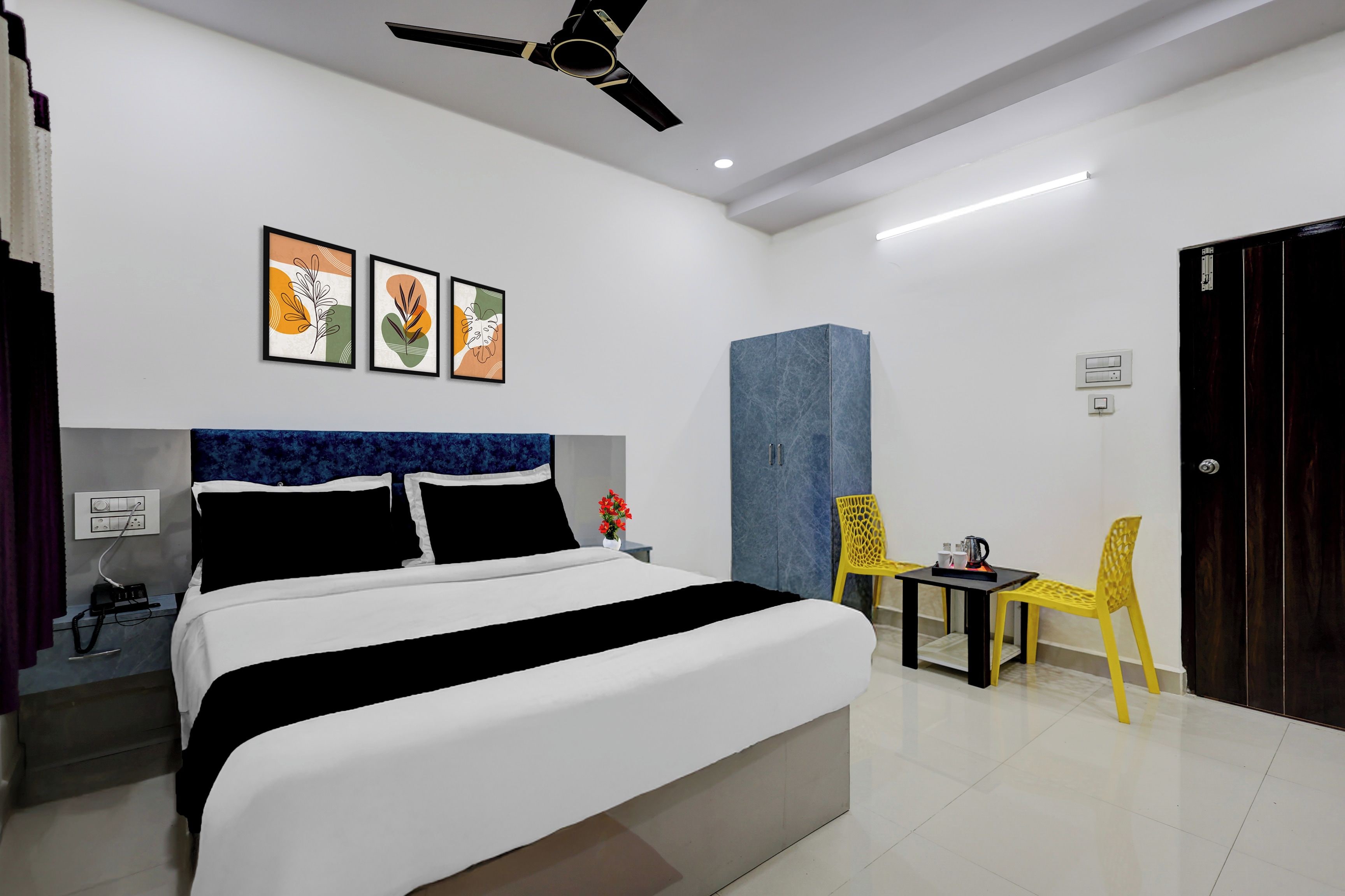 A hotel room with a bed, a desk, a chair, a wardrobe, and a ceiling fan.