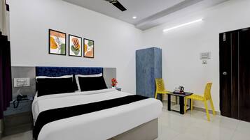 A hotel room with a bed, a desk, a chair, a wardrobe, and a ceiling fan.