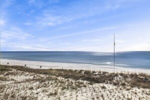 Ein Strand mit sandigem Vordergrund und blauem Himmel.