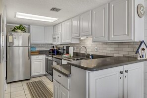 A modern kitchen with white cabinetry, stainless steel appliances, and a tiled backsplash. - Tequila Sunrise at Pinnacle Port B1-308 (Panama City Beach)