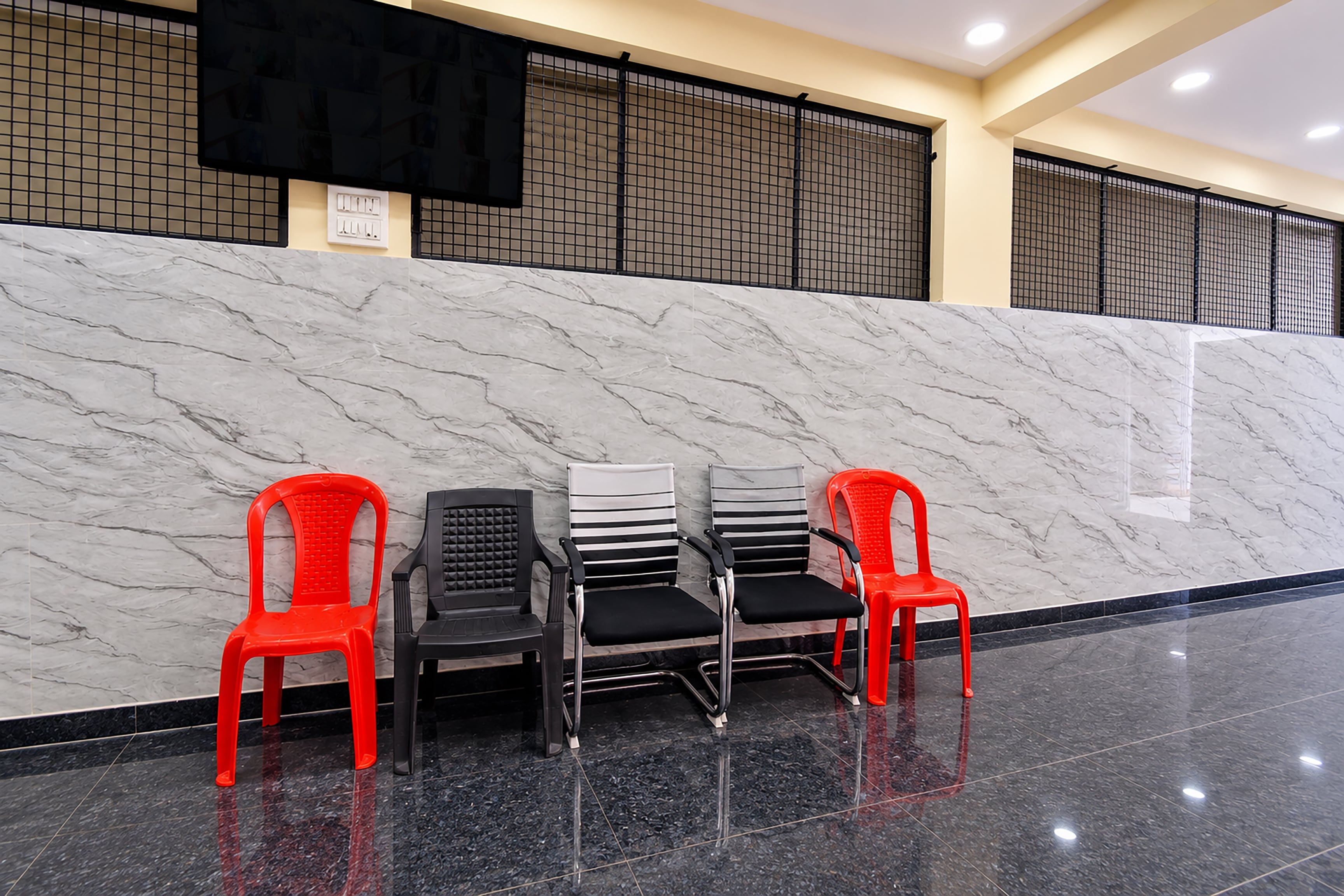 Un espace d’accueil avec un mur en marbre, un fauteuil à rayures noires et blanches et un fauteuil rouge.