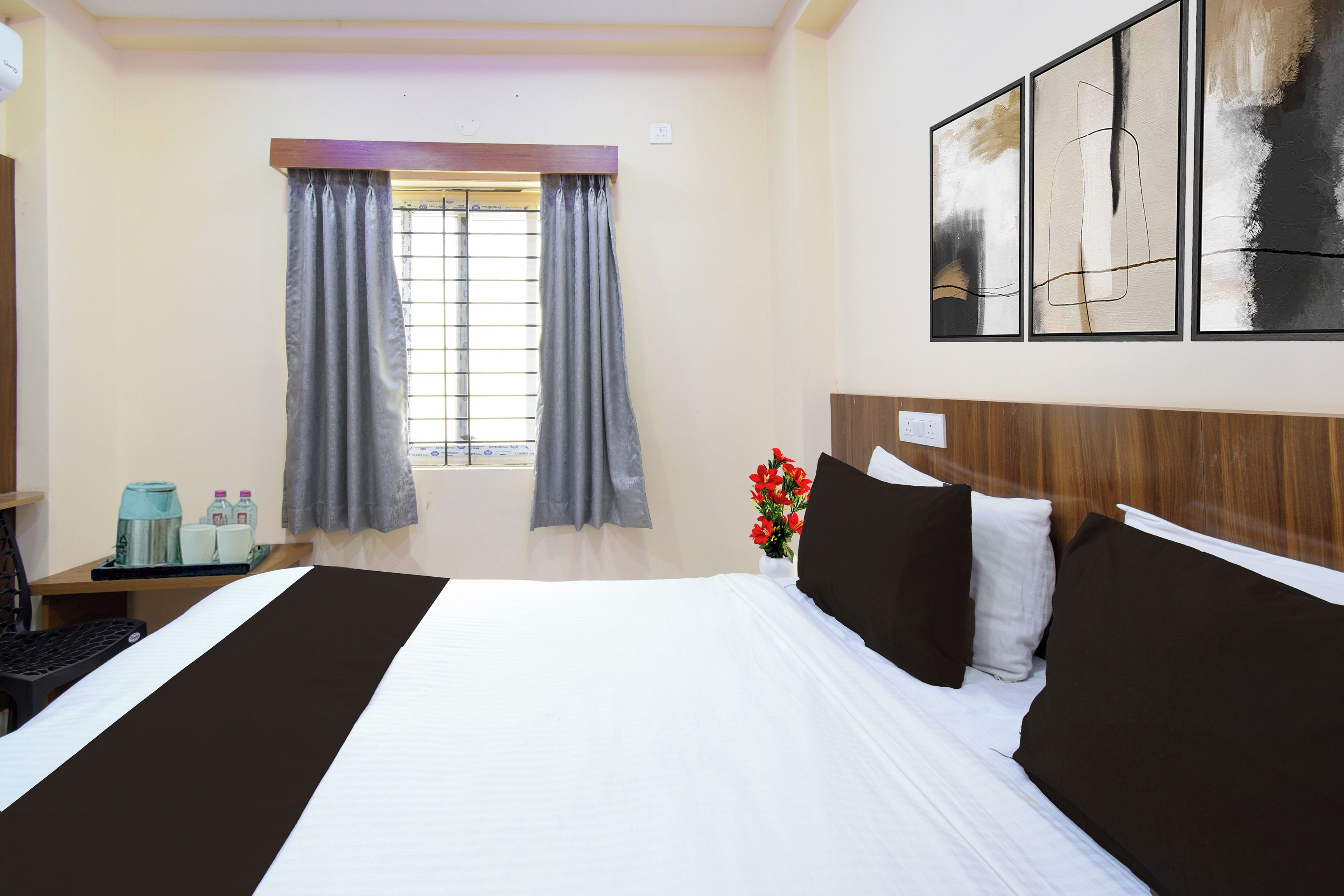 Une chambre d’hôtel avec un grand lit, un bureau avec un ordinateur, une fenêtre avec des rideaux et un tableau au mur.