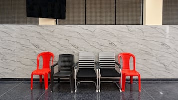 Een receptie met een marmeren wand, een zwart scherm en vier stoelen in verschillende stijlen.