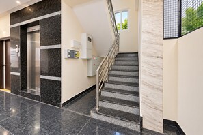Un interno moderno con una scalinata in marmo, un ascensore e un pannello di controllo.