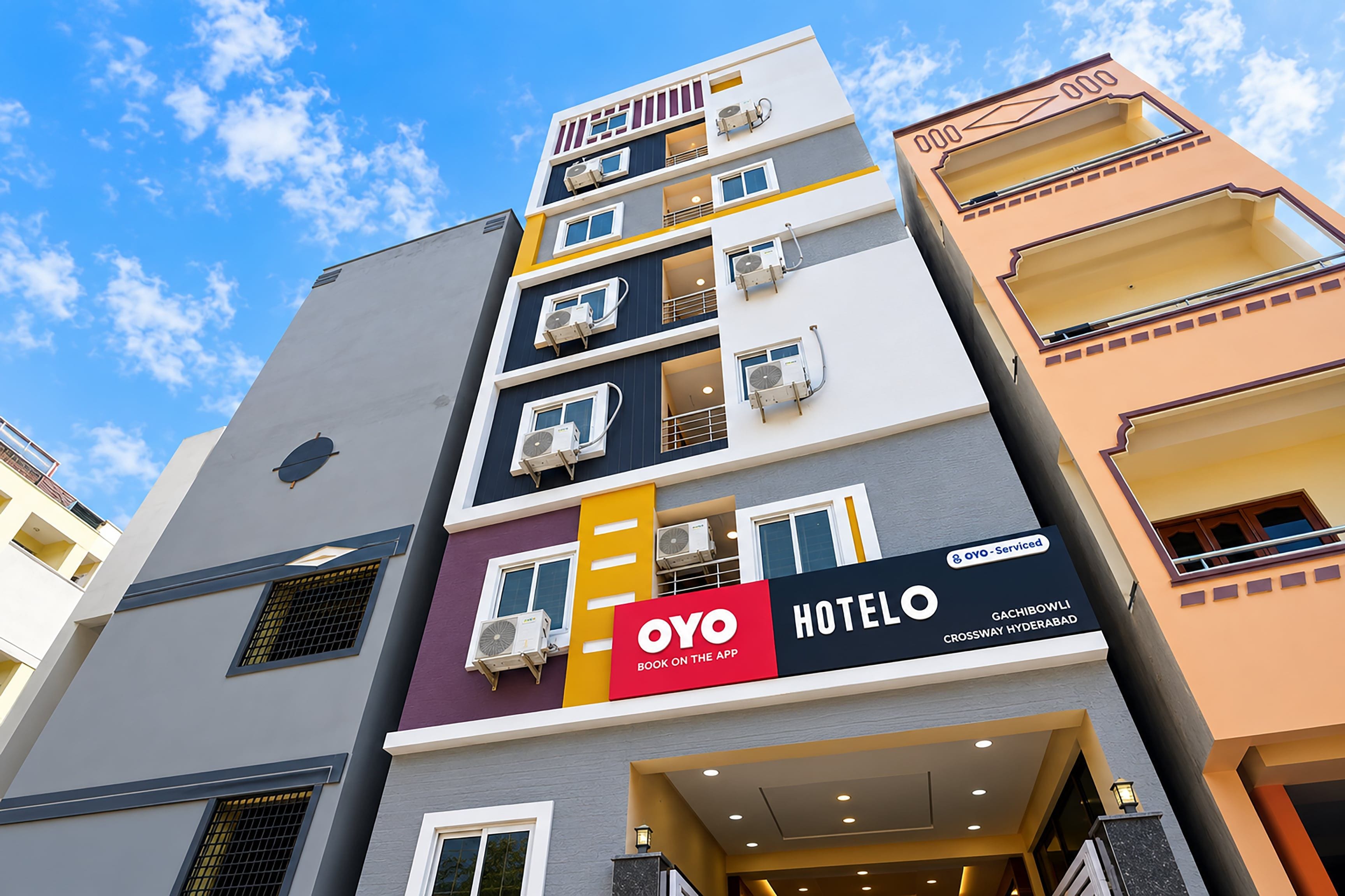 Un hôtel à plusieurs étages, doté de balcons, de climatiseurs et d’une enseigne bien visible.