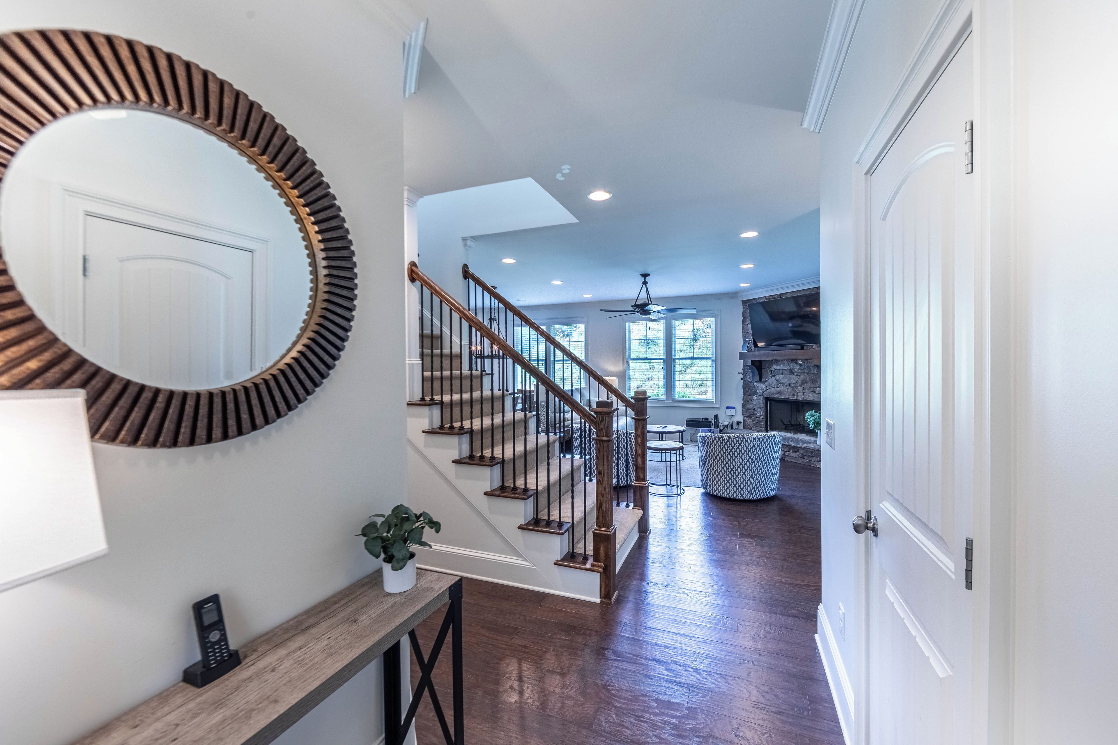 A staircase with wooden railings and a handrail, leading to a living area with a fireplace and a stone wall.