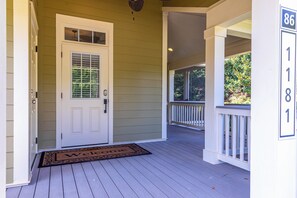 A house entrance with a white door, a welcome mat, and a porch with a railing. - 3BR home in Reynolds Landing with patio, grill & foosball (Greensboro)