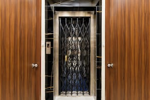 Un ascensor con una puerta metálica y puertas de madera.