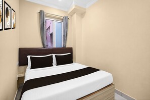 Un dormitorio con una cama, una ventana con cortinas y obras de arte enmarcadas en la pared.