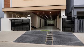 A covered walkway leading to a building entrance with a modern design, featuring a ramp and a gated entrance.