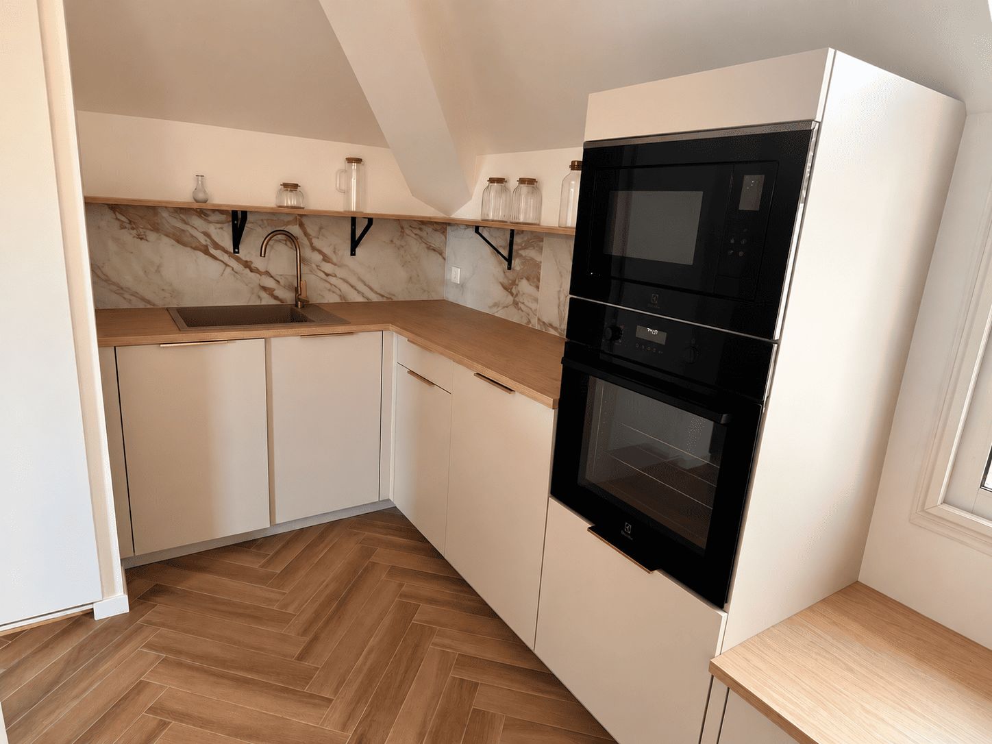 A kitchen with white cabinets, a wooden countertop, a black oven, and a marble backsplash.