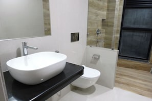 Un baño moderno con lavamanos blanco, inodoro y cabina de ducha de vidrio.