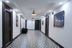 A hallway with patterned flooring, dark doors, and a ceiling light fixture. - Sama Inn (Rishikesh)