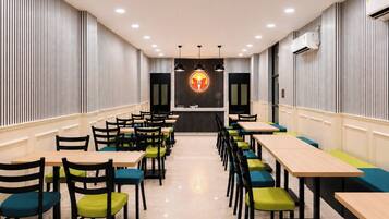 A restaurant with a central counter, multiple tables, and chairs.