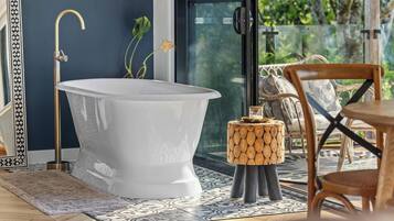 Ein modernes Badezimmer mit einer freistehenden Badewanne, einem Holztisch und einem Stuhl.