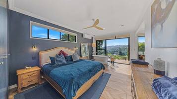Ein Schlafzimmer mit einem großen Bett, einem Deckenventilator, Blick ins Freie und einer Badewanne.