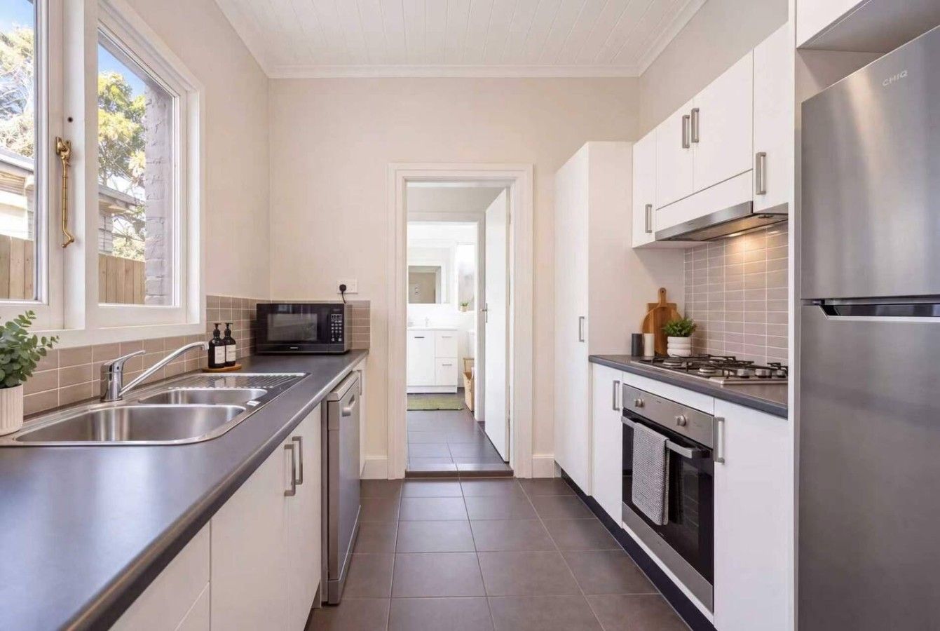 Una cocina moderna con electrodomésticos de acero inoxidable, microondas y vistas al área de estar contigua.