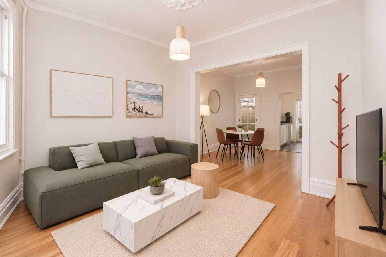 A modern living room with a green sofa, a marble coffee table, and a dining area with a table and chairs.