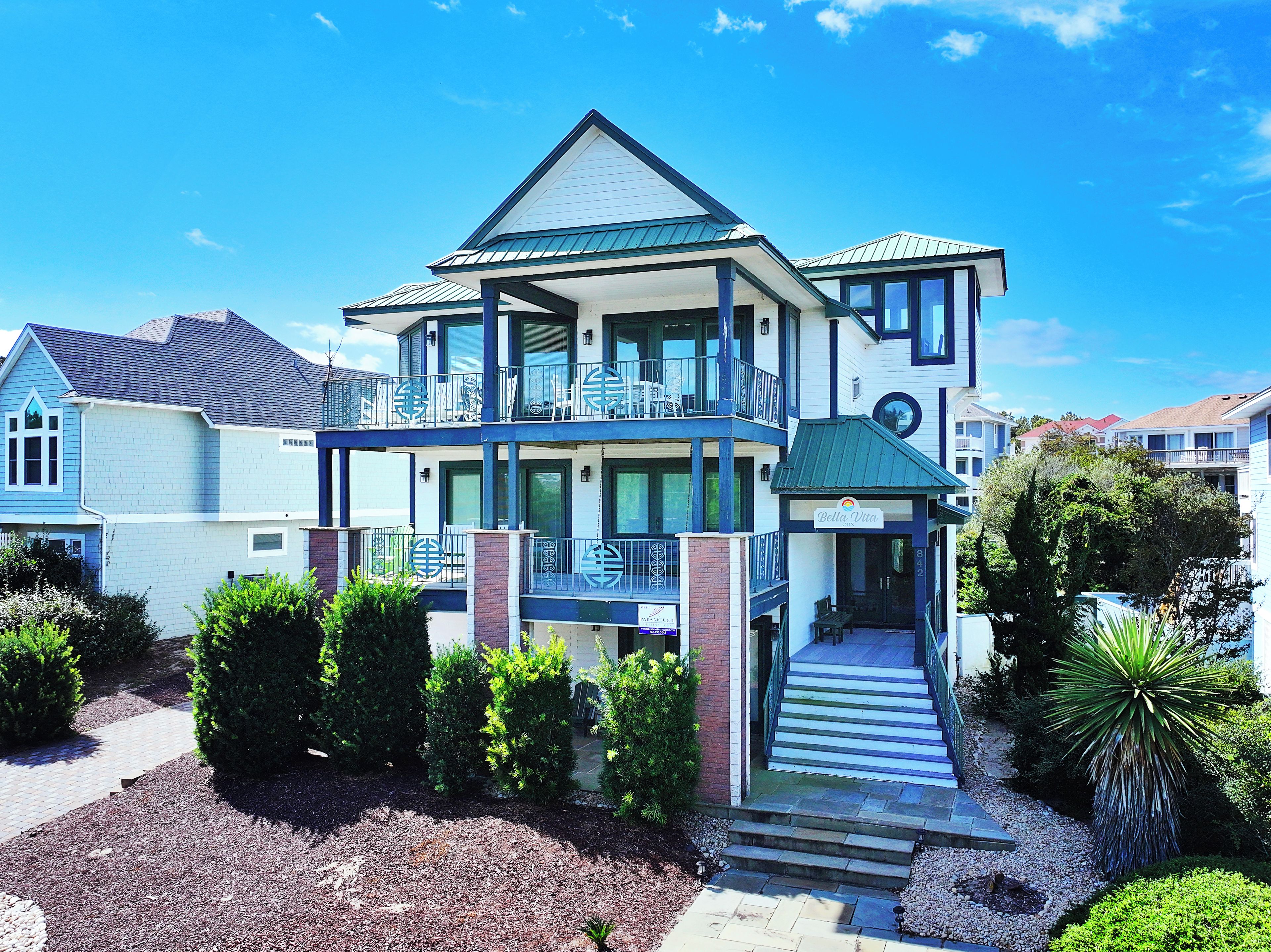 A two-story residential building with a balcony, a covered porch, and a driveway leading to the entrance.
