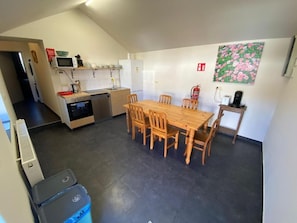 Una cocina con mesa y sillas, microondas y extintor.
