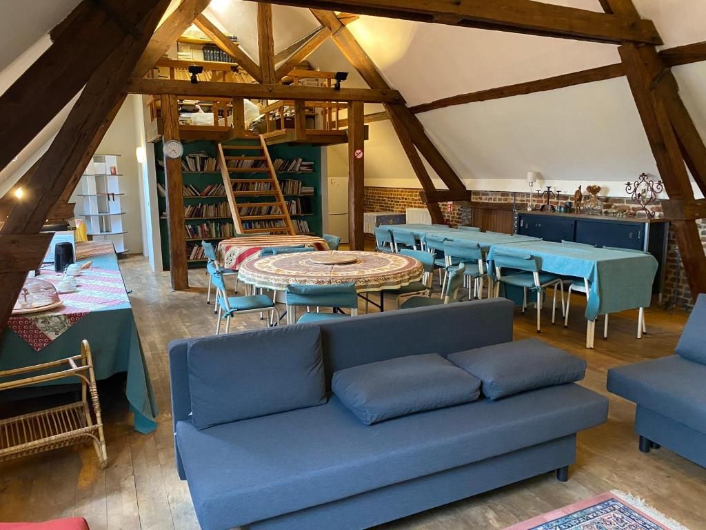 A cozy attic room with a blue sofa, a round table, and a bookshelf.