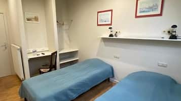 A room with two single beds, a desk, and a chair.