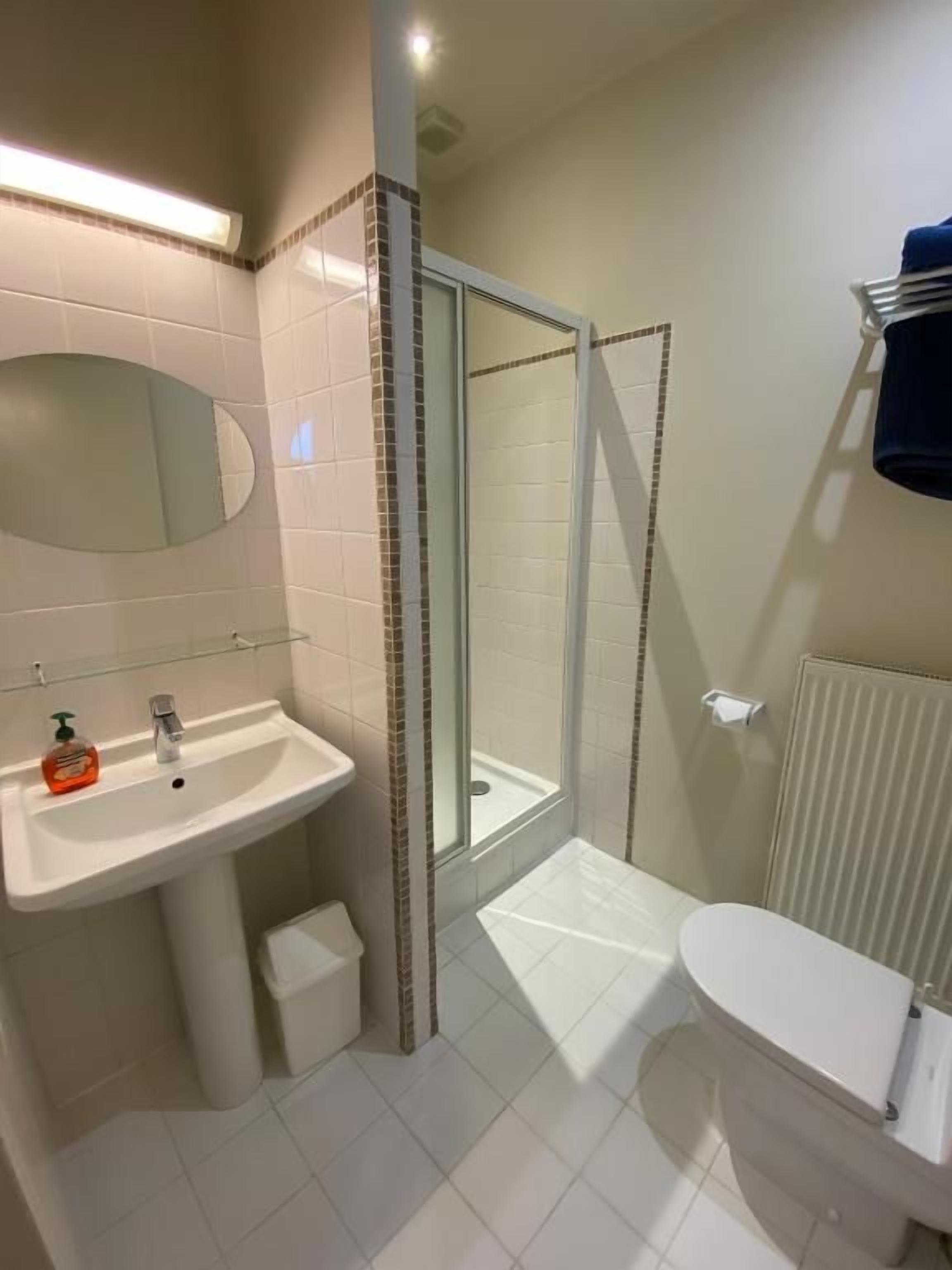 Un baño con lavamanos, espejo, inodoro y zona de ducha.