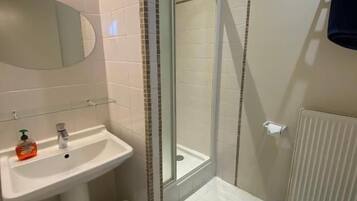 Un baño con lavamanos, espejo, inodoro y zona de ducha.