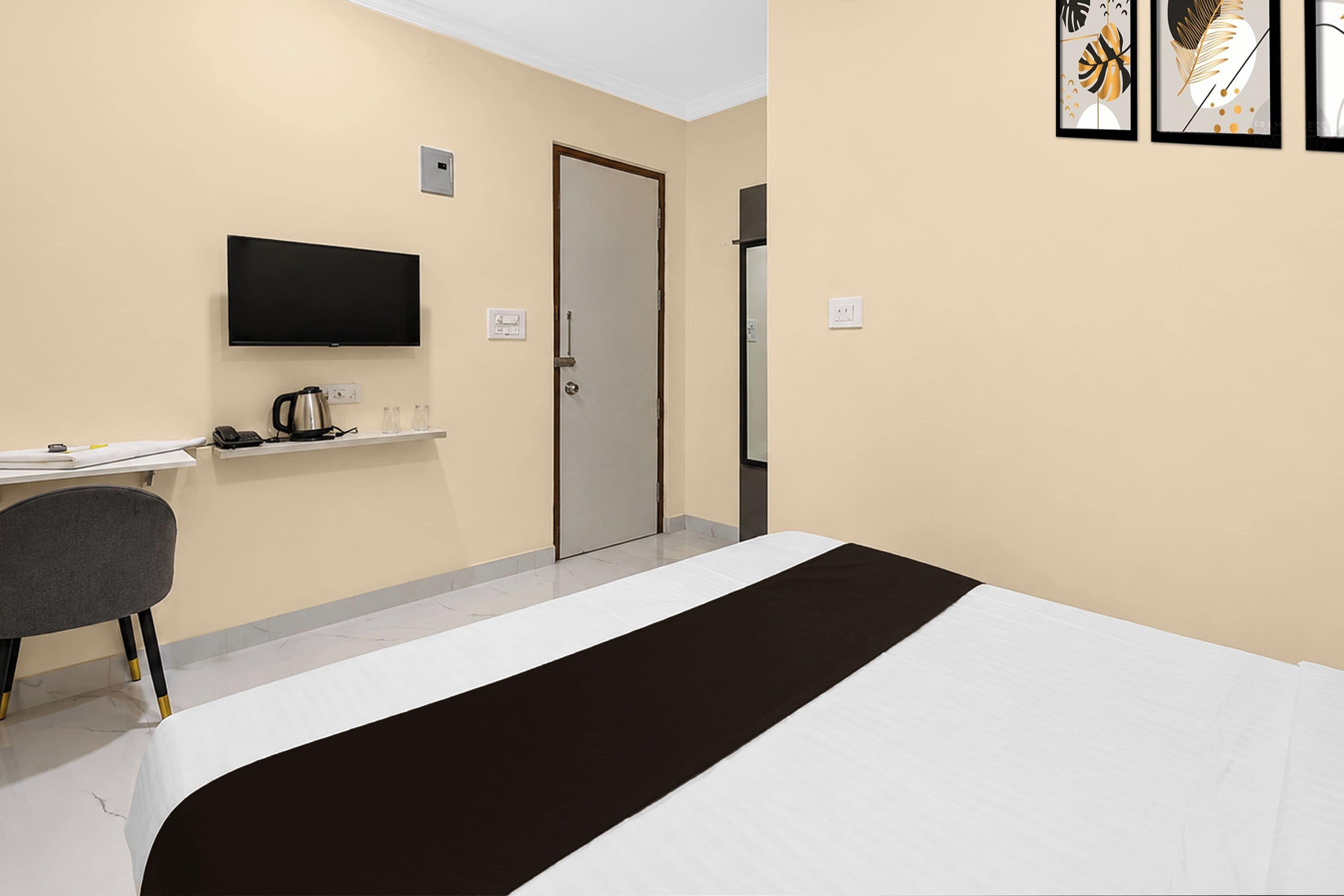 A hotel room with a bed, a desk, a chair, a television, and a door.