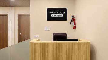 En receptionsdisk med en skylt ovanför som lyder: ”TOWNHOUSE YOYO – serviceinriktat”. En brandsläckare är monterad på väggen till höger om disken.