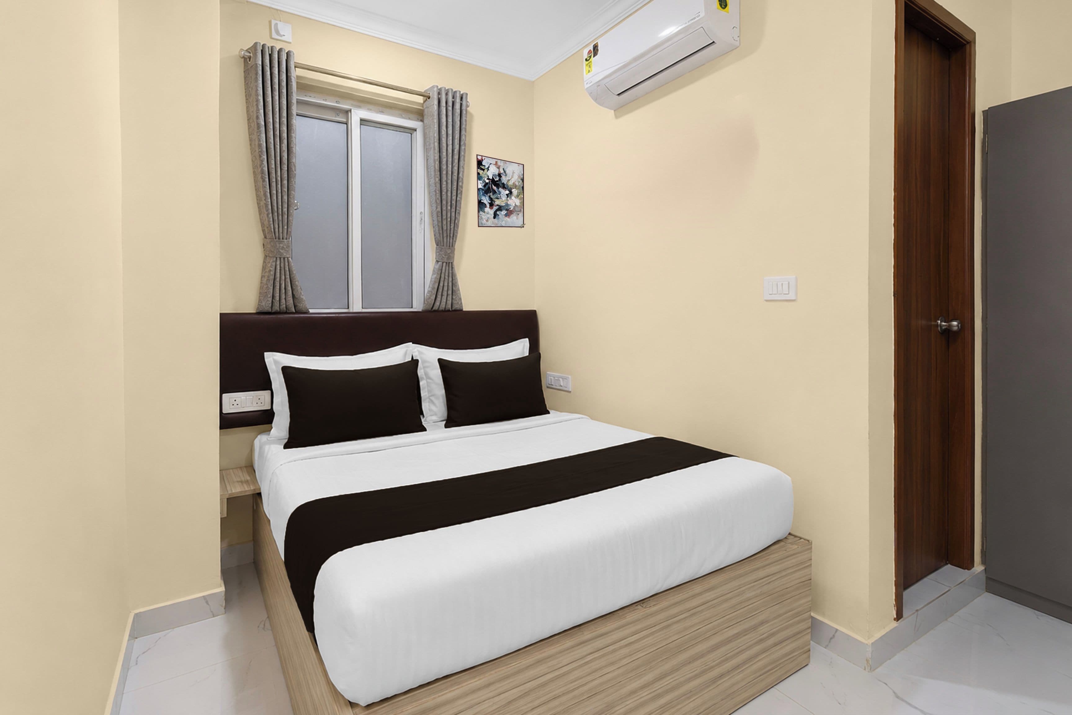 Une chambre à coucher avec un lit, une fenêtre avec des rideaux, un appareil de climatisation et une porte.