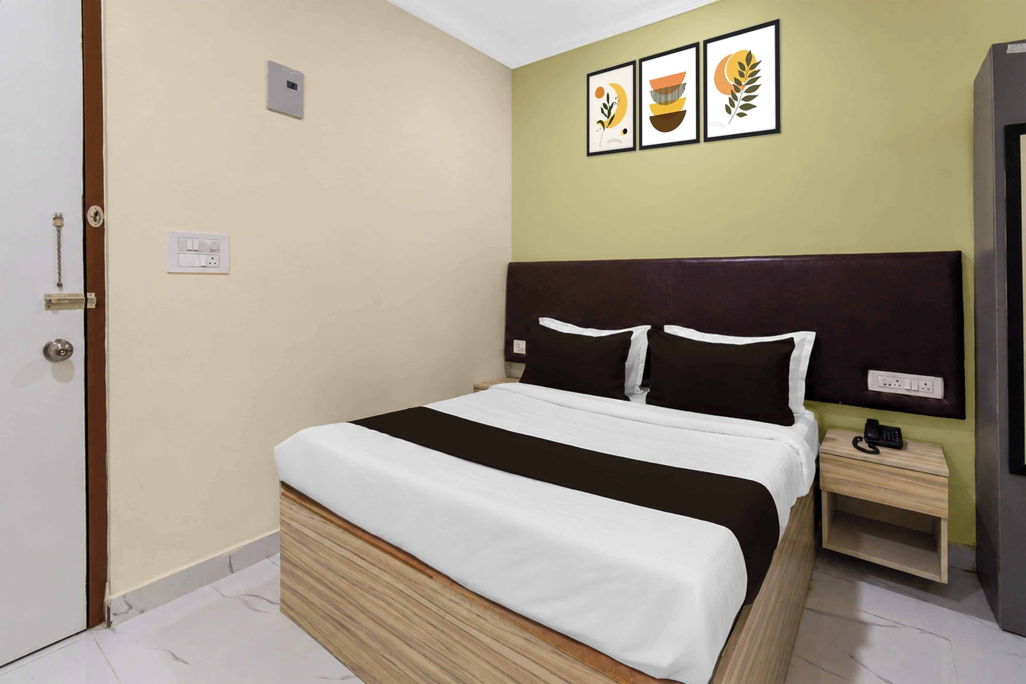 Una habitación de hotel con cama, mesita de noche y toma de corriente en la pared.