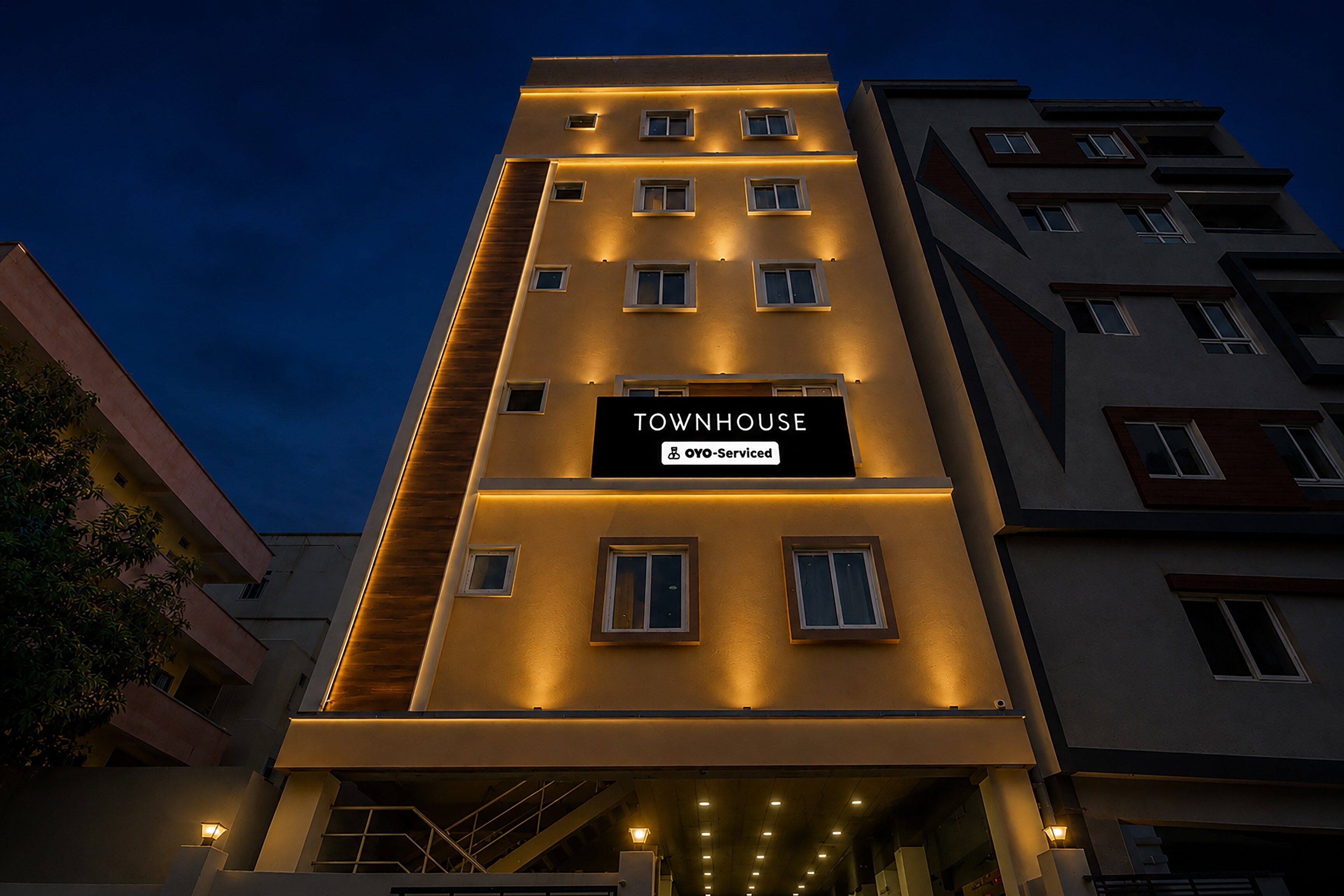 Un edificio de varios pisos con un letrero que dice 'TOWNHOUSE' y 'OYO-Serviced'.