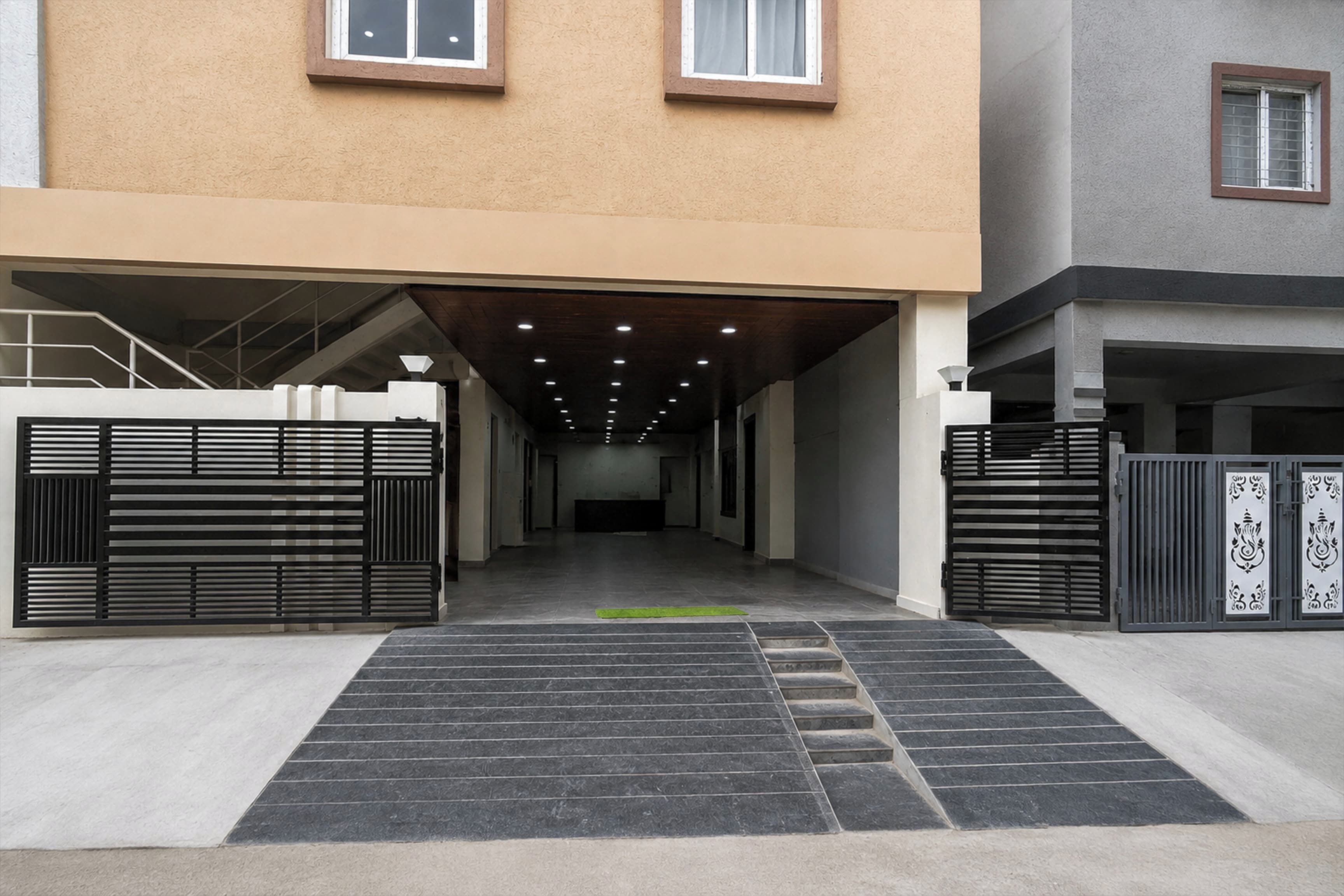 A building entrance with a covered walkway, metal gates, and a staircase leading to an upper level.