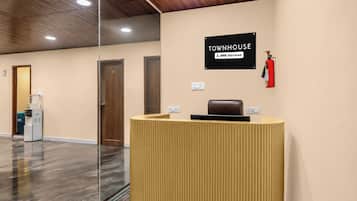 A reception desk with a sign indicating it is serviced by OYO, a reception area with a fire extinguisher, and a water dispenser.