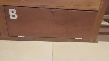 A wooden cabinet with a lock, a visible letter 'B' on the side, and a tiled floor.