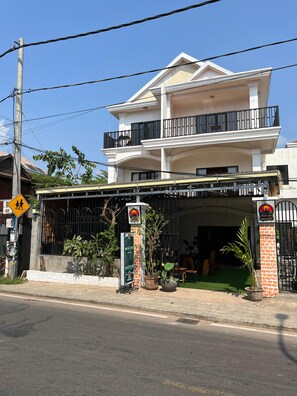 Edificio de dos plantas con un porche cubierto y un camino de entrada cerrado por una reja.