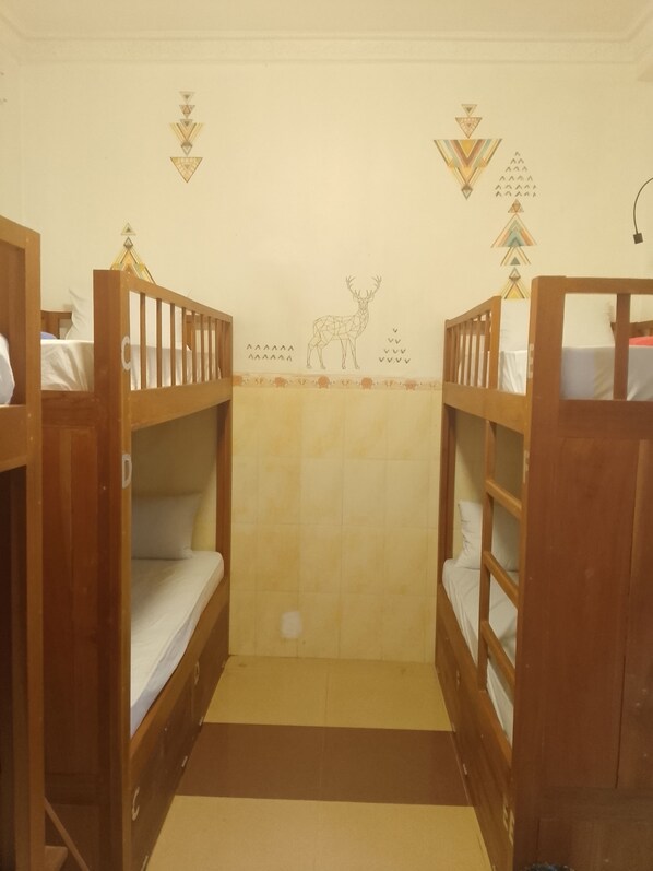 A room with two wooden bunk beds, a tiled wall with geometric patterns, and a small rug on the floor. - The Han Angkor Hotel (Siem Reap)