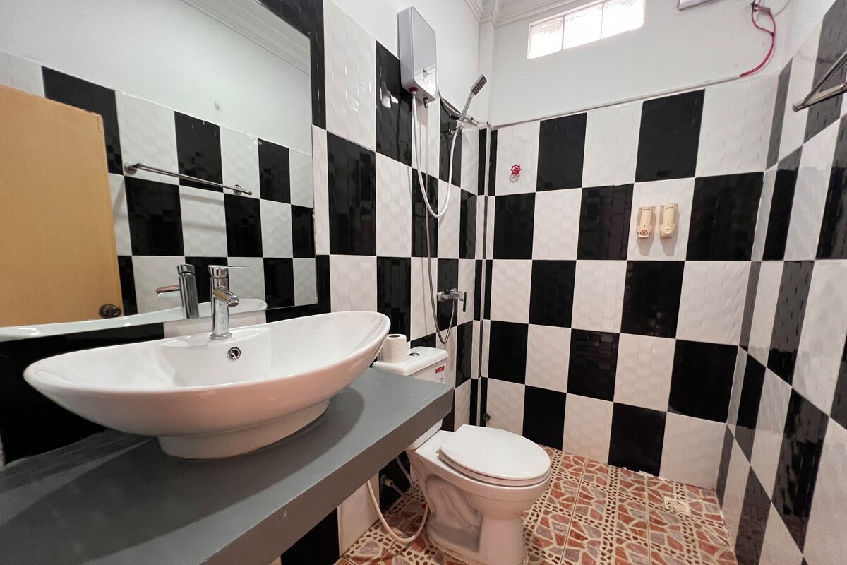 Un baño con lavamanos blanco, inodoro y zona de ducha.