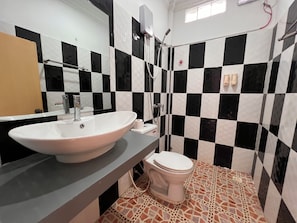 Un baño con lavamanos blanco, inodoro y zona de ducha.