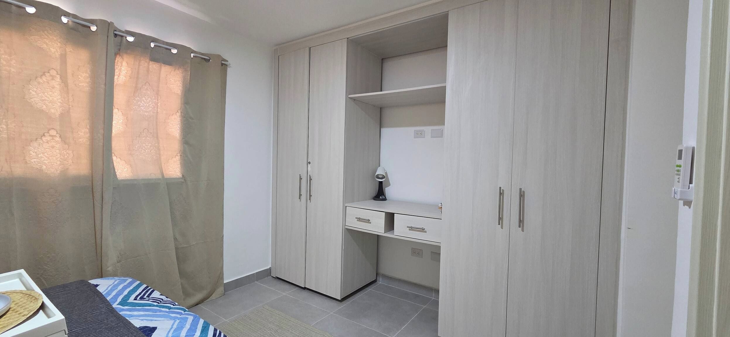 Un dormitorio con una cama, un armario y una zona de escritorio.