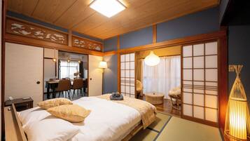 A traditional Japanese-style room with a bed, a dining area, and sliding doors.