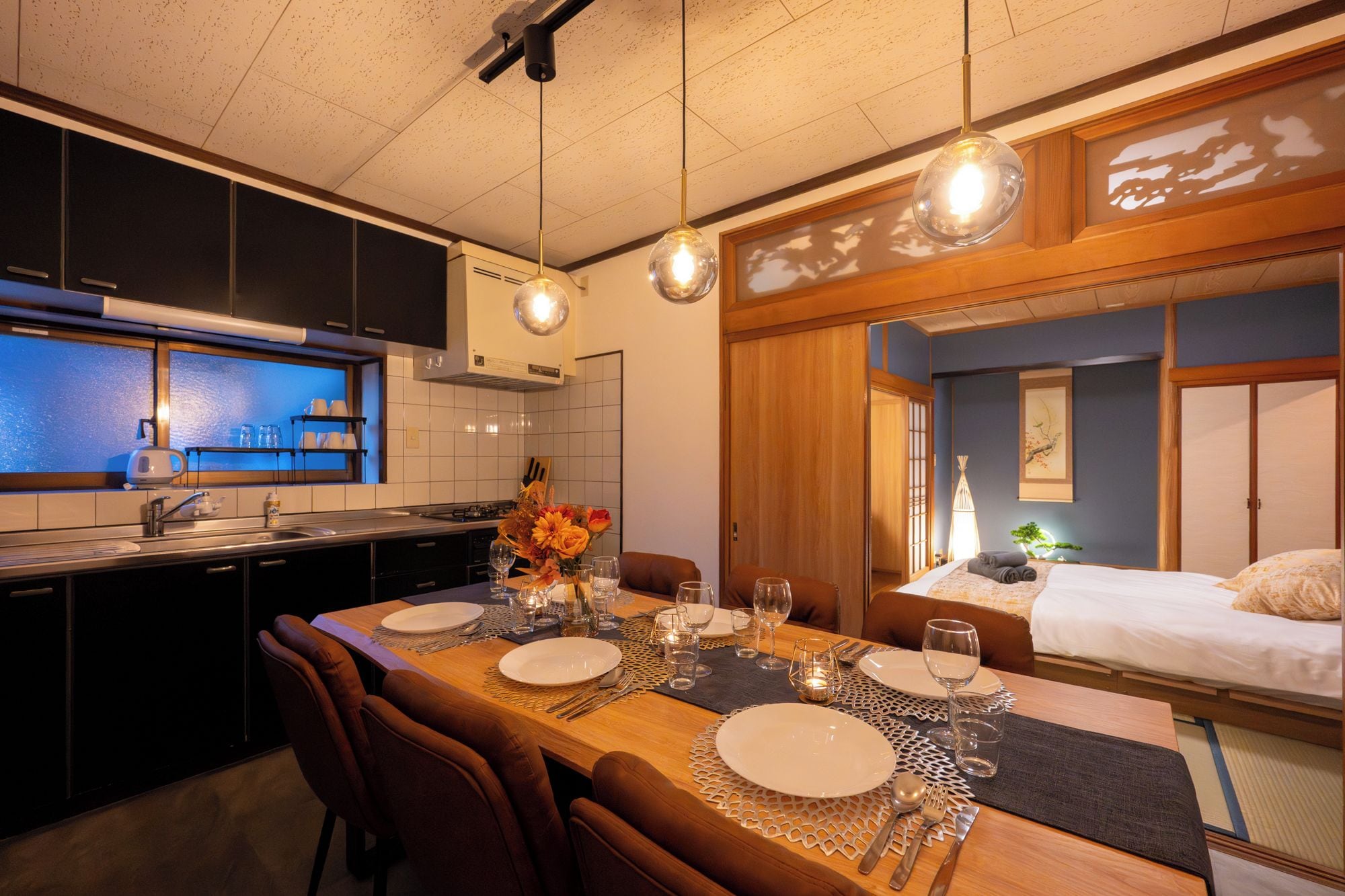 A modern kitchen with a dining area, a bed, and a view of the outside.