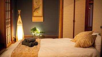 A neatly made bed with a blanket and pillows, a bedside lamp, and a wall-mounted painting.