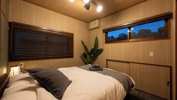 A bedroom with a bed, a window with a view, a plant, and a ceiling light fixture.
