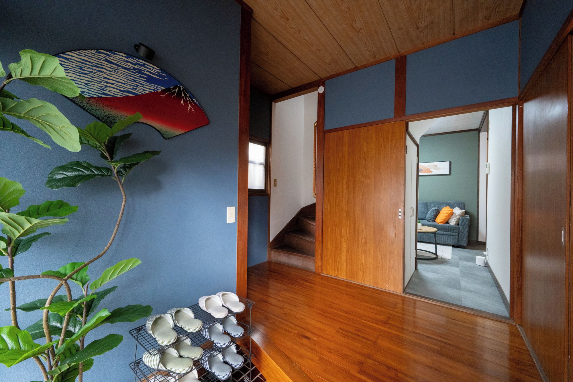 A traditional Japanese interior with a wooden floor, sliding doors, and a plant with large leaves.