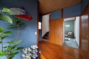 Um interior japonês tradicional com soalho de madeira, portas deslizantes e uma planta de folhas grandes.