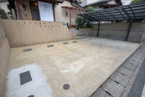 Un espace extérieur en béton doté d’une structure de toit en métal, d’un mur avec une porte et d’une banderole.