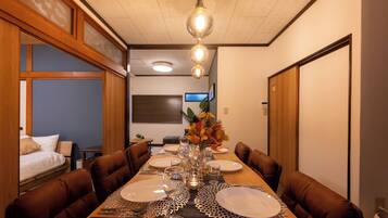 A dining area with a long wooden table set for a meal, surrounded by brown upholstered chairs.